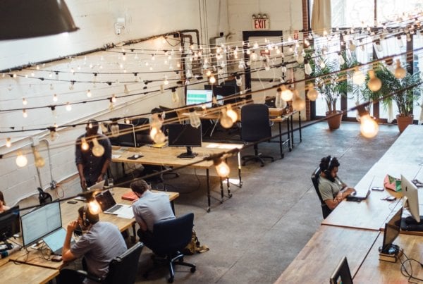 People working under string lights in a bright and airy coworking space